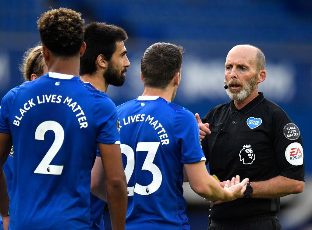 LIVERPOOL, ENGLAND - JUNE 21: Match referee Mike Dean looks on while the NHS logo is seen on his shirt during the Premier League match between Everton FC and Liverpool FC at Goodison Park on June 21, 2020 in Liverpool, England. Football Stadiums around Europe remain empty due to the Coronavirus Pandemic as Government social distancing laws prohibit fans inside venues resulting in all fixtures being played behind closed doors. (Photo by Peter Powell/Pool via Getty Images)