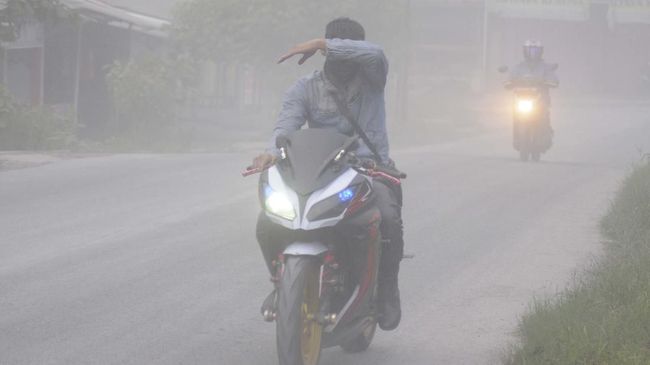 Pengendara motor menutupi wajahnya saat terjadi hujan abu di Mojosongo, Boyolali, Jawa Tengah, Selasa (3/3/2020). Hujan abu terjadi di beberapa wilayah Boyolali akibat erupsi Gunung Merapi pada pukul 05.22 WIB dengan tinggi kolom 6.000 meter. ANTARA FOTO/Aloysius Jarot Nugroho/pras.