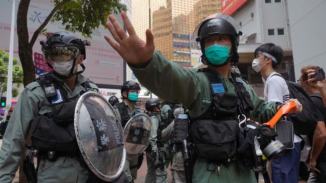 Riot police form a line and issue warnings as they plan to clear away people gathered in the Central district of Hong Kong Wednesday, May 27, 2020. Hong Kong police massed outside the legislature complex Wednesday, ahead of debate on a bill that would criminalize abuse of the Chinese national anthem in the semi-autonomous city. (AP Photo/Vincent Yu)