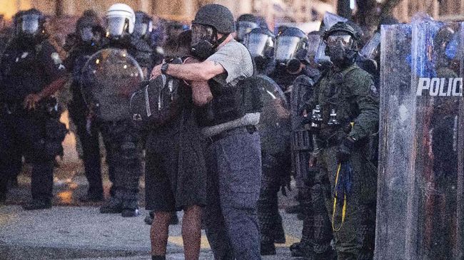 A police officer embraces a protester who helped disperse a crowd of people during a demonstration Monday, June 1, 2020, in Atlanta over the death of George Floyd, who died after being restrained by Minneapolis police officers on May 25. (AP Photo/John Bazemore)