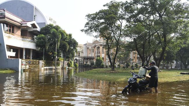 Pengendara motor menata barang bawaannya di atas motor yang mogok akibat banjir rob di Kompleks Pantai Mutiara, Penjaringan, Jakarta, Minggu (7/6/2020). Banjir di kawasan tersebut diduga akibat adanya tanggul yang jebol saat naiknya permukaan air laut di pesisir utara Jakarta. ANTARA FOTO/Hafidz Mubarak A/foc.