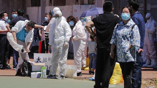 Workers put on protective suits as they wait for people living surrounding the Xinfadi wholesale market arrive to get a nucleic acid test at a stadium in Beijing, Sunday, June 14, 2020. China is reporting its highest daily total of coronavirus cases in two months after the capital's biggest wholesale food market was shut down following a resurgence in local infections. (AP Photo/Andy Wong)