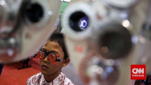 Volunteers conduct an eye examination on an elementary school student during a free eye examination and glasses event at GOR Grogol, West Jakarta, Thursday, October 9 2014. The series of events involving around 3,000 school-aged children from various Presidential Instruction schools in the Jakarta area were held to commemorate World Sight Day and raise awareness of the prevention and treatment of visual impairment.  Armfalcon.com/Adhi Wicaksono.