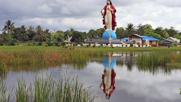 Warga melintas dekat Patung Hati Kudus Yesus di Merauke, Papua, Sabtu (21/3). Patung setinggi 12 meter yang merupakan ikon kota paling timur Indonesia tersebut dibangun dengan biaya Rp15 miliar dan diresmikan pada 14 Agustus 2011 guna memperingati hari pertama masuknya Gereja Katolik di Merauke 106 tahun yang lalu. ANTARA FOTO/Akbar Nugroho Gumay/mes/15