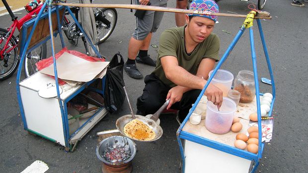 Kerak Telor vendor on Jakarta street. Kerak Telor is traditional Betawi spicy omelette dish. Made from the mixture of rice, egg, spices, spicy coconut granule, and fried shallots.