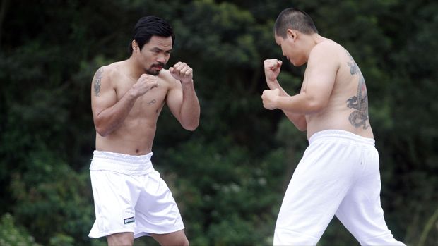 Petinju Filipina Manny Pacquiao (tengah) berakting dengan petinju Indonesia Chris John (kanan) pada proses pembuatan iklan jamu PT Sido muncul di lereng Gunung Merapi, Sleman, Kamis (9/7). Menurut pihak  PT Sido Muncul dipakainya Manny sebagai bintang iklan terbaru Kuku Bima Energi sebagai antisipasi  diberlakukannya Masyarakat Ekonomi Asean (MEA) karena iklan akan diputar di sejumlah negara Asean, maka harus direfleksikan oleh seorang tokoh terkenal dunia dan memiliki kepedulian tinggi pada sesama. ANTARA FOTO/Regina Safri/Rei/nz/15.