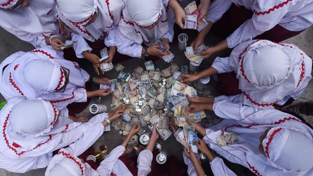 UANG JAJAN LEBARAN UNTUK DUAFA Sejumlah murid SD Al Falah Surabaya menghitung uang tabungan selama libur Lebaran ketika hari pertama masuk sekolah di halaman Sekolah mereka, Surabaya, Jawa Timur, Senin (27/7). Hasil uang tabungan para siswa tersebut selanjutnya diberikan kepada kaum duafa. ANTARA FOTO/Zabur Karuru/Rei/pd/15.