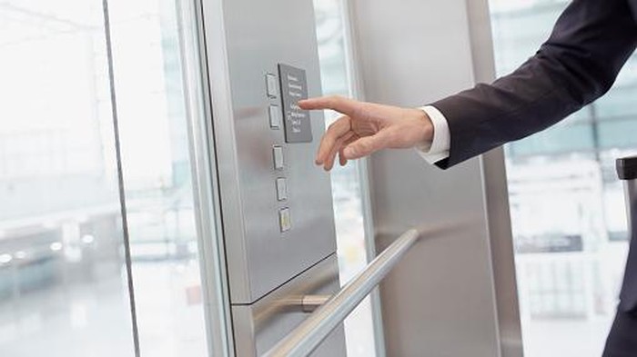 Hand of businessman pressing control in elevator