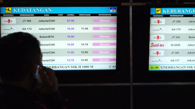 Calon penumpang pesawat mengamati layar informasi jadwal penerbangan yang menunjukan penundaan (delayed) kedatangan dan keberangkatan di Bandara Sultan Syarif Kasim II Pekanbaru, di Pekanbaru, Riau, Senin (28/9). Kabut asap kebakaran hutan dan lahan yang kembali menyelimuti Kota Pekanbaru menyebabkan sedikitnya 25 jadwal penerbangan dibatalkan. ANTARA FOTO/Rony Muharrman/aww/15.