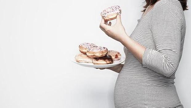 Pregnant woman holding plate of doughnuts