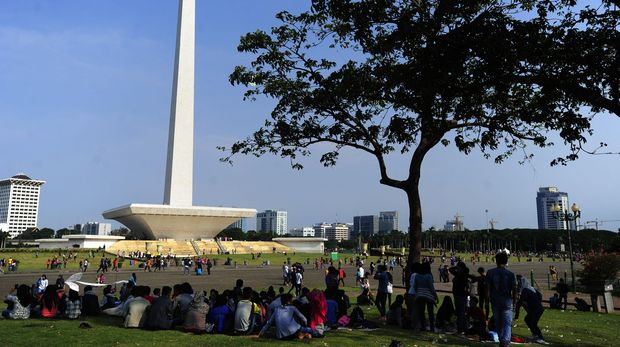 Warga duduk di rumput ketika mengunjungi Kawasan Monas, Jakarta, Jumat (1/1). Monas yang merupakan Ikon Ibu Kota itu menjadi salah satu tujuan wisata untuk mengisi libur tahun baru. ANTARA FOTO/Wahyu Putro A/nz/15