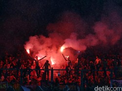 Beberapa suporter menyalakan kembang api dari atas tribun.