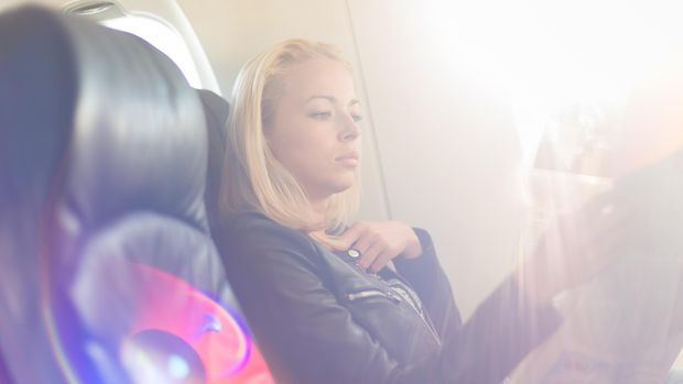 Woman reading newspaper on airplane. Ilustrasi Penumpang di Kabin Pesawat. kasto80/Thinkstock