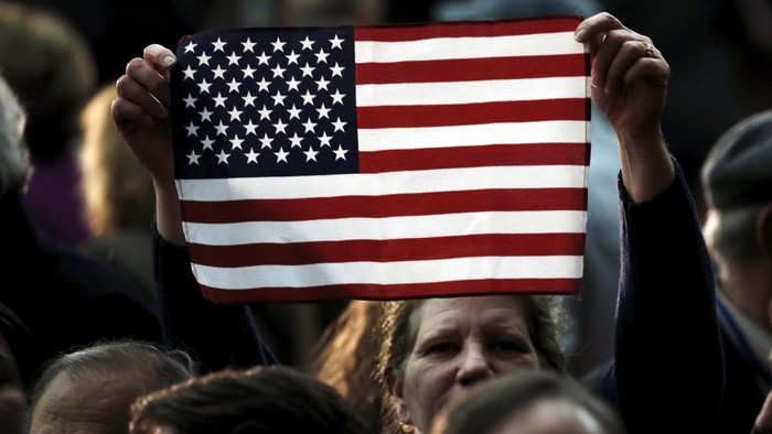 Ilustrasi Bendera Amerika Serikat A supporter of Republican presidential candidate Donald Trump holds an American flag as Trump speaks at a campaign rally in Milford, New Hampshire, February 2, 2016. REUTERS/Mike Segar
