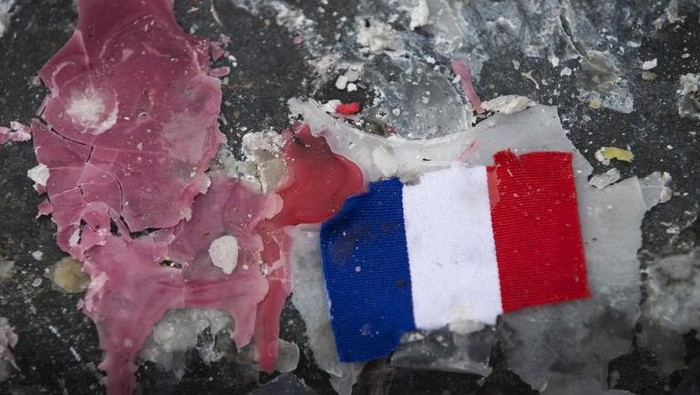 A picture shows a small French flag on candle wax on the Place de la Republique in Paris on December 2, 2015, at a memorial for victims of coordinated attacks in and around Paris on November 13. Islamic State jihadists claimed a series of coordinated attacks by gunmen and suicide bombers in Paris that killed 130 people and wounded hundreds more in scenes of carnage at a concert hall, restaurants and the national stadium. / AFP / JOEL SAGET Aljazair Usir 12 Pejabat Prancis