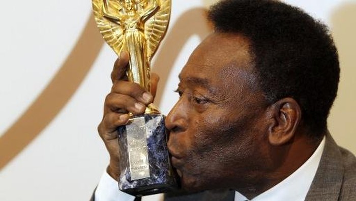 Former Brazilian footballer Pele kisses a replica Jules Rimet trophy, a trophy awarded to the winner of the football World Cup, during an media interview at a preview for an auction of his memorabilia in London on June 1, 2016.  
The three-time World Cup winner and FIFA Player of the Century is offering to auction his vast memorabilia collection including awards, personal property and iconic items from his entire career. The collection is being offered by Juliens Auction House on June 7, 8, 9 in London. / AFP PHOTO / ADRIAN DENNIS