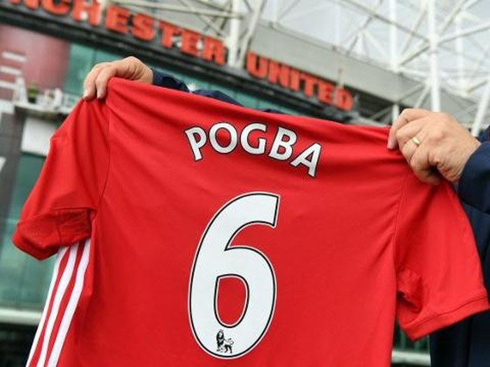 A man poses for pictures after purchasing a Manchester United shirt with the name and squad number of recent signing French midfielder Paul Pogba outside Old Traford in Manchester, north west England, on August 9, 2016.
The world record for a transfer fee was shredded Tuesday when French superstar Paul Pogba completed a sensational return to Manchester United from Juventus for 105 million euros ($116 million). / AFP PHOTO / PAUL ELLIS
