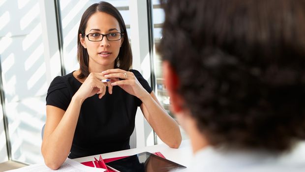 Businesswoman Interviewing Male Candidate For Job Holding Pen With Digital Tablet On Table