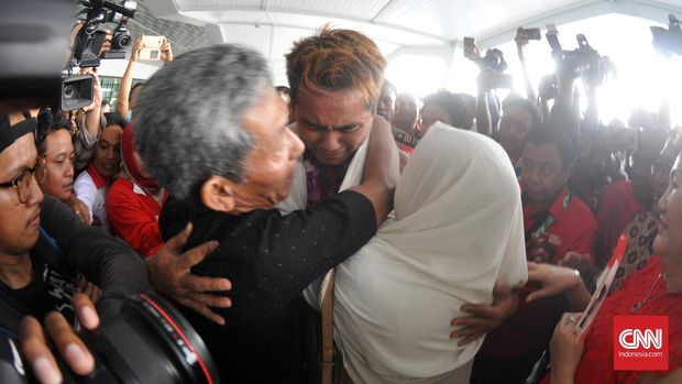 Tontowi Ahmad tak kuasa menahan tangis saat berpelukan dengan kedua orang tua, M. Husni Muzaitun dan Masruroh.(CNN Indonesia/Putra Tegar)