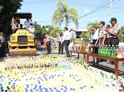 Sebuah Backhoe Hancurkan Ribuan Botol Miras Berbagai Jenis