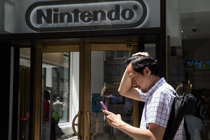 Nintendo logo NEW YORK, NY - JULY 11: A man plays Pokemon Go on his smartphone outside of Nintendos flagship store, July 11, 2016 in New York City. The success of Nintendos new smartphone game, Pokemon Go, has sent shares of Nintendo soaring. (Photo by Drew Angerer/Getty Images)