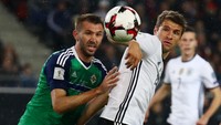 Gareth McAuley (kiri) berebut bola dengan Thomas Muller (kanan) pada pertandingan yang dihelat di HDI-Arena, Hannover, Rabu (12/10/2016) dinihari WIB. Kai Pfaffenbach/Reuters/detikFoto.