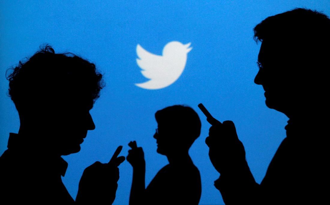 People holding mobile phones are silhouetted against a backdrop projected with the Twitter logo in this illustration picture taken in  Warsaw September 27, 2013.   REUTERS/Kacper Pempel/Illustration/File Photo