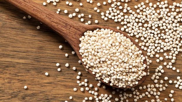 Quinoa seeds in a wooden spoon shot directly above on wood background. Some seeds are dropped out the spoon. DSRL studio photo taken with Canon EOS 5D Mk II and Canon EF 100mm f/2.8L Macro IS USM