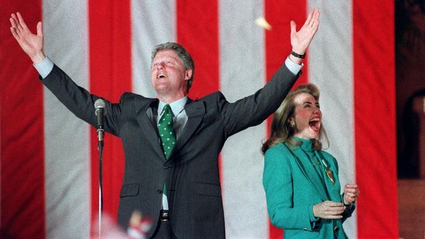 Democratic presidential candidate Bill Clinton waves to the crowd with his wife Hillary during his victory party after winning the Illinois primary, 17 March 1992 in Chicago. / AFP PHOTO / TIMOTHY A. CLARY