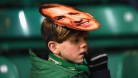 Seorang bocah memakai topeng Brendan Rodgers, manajer Celtic. Bermain di kandang, Celtic kalah 0-2 dari Barcelona. (Foto: Mike Hewitt/Getty Images)