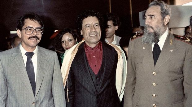 Fidel Castro, Muammar Khadafi, Daniel Ortega Libyan leader Moamer Kadhafi (C) and Cuban president Fidel Castro (R) walk along with Nicaraguan president Daniel Ortega (L) during the non-aligned countries summit, on September 4, 1986 in Harare, Zimbabwe. / AFP PHOTO / ALEXANDER JOE AND DOMINIQUE FAGET