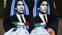 Suporter Chelsea membaca matchday programme sebelum laga The Blues dengan Tottenham Hotspur. Terlihat wajah Antonio Conte menghiasi syal miliknya. (Foto: Clive Rose/Getty Images)