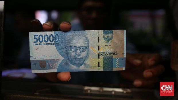 Petugas menujukkan gambar Djuanda Kartawidjaja dalam uang pecahan Rp50 ribu, di Blok M Square, Jakarta, 2016.