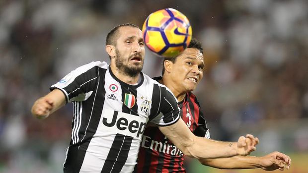 Juventus' Giorgio Chiellini (L) vies for the ball against AC Milan's Carlos Bacca during the Italian Super Cup final match between AC Milan and Juventus in Doha on December 23, 2016. / AFP PHOTO / KARIM JAAFAR