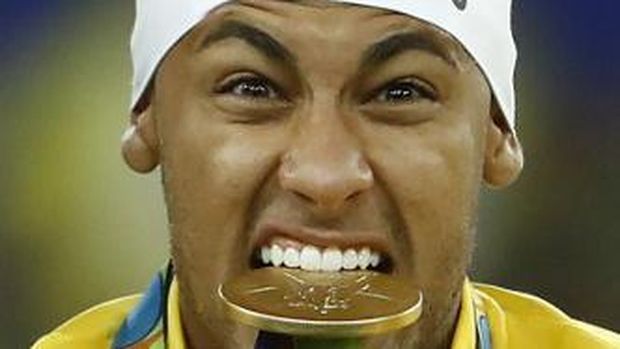 Brazil's Neymar bites his medal on the podium during the medal presentation following the Rio 2016 Olympic Games men's football gold medal match between Brazil and Germany at the Maracana stadium in Rio de Janeiro on August 20, 2016.  / AFP PHOTO / Odd Andersen