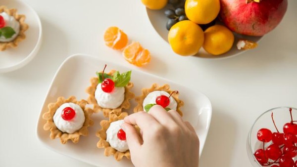 kue manis Closeup of a continental breakfast at a hotel restaurant, with bowls and plates filled with a selection of breakfast bakery items and fresh fruit on a blue tablecloth with cutlery in the background.