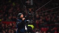 Seorang teknisi memperbaiki spider cam di Old Trafford. Spider cam adalah kamera yang merambat di antara kabel-kabel di atas lapangan yang kerap memberi gambar high angle di tengah laga. (Foto: Laurence Griffiths/Getty Images)