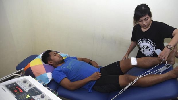 Pesepak bola tim nasional Indonesia Andik Vermansyah (kiri) menjalani terapi penyembuhan cedera di Physiopreneur Sport Physiotherapy kawasan Surabaya Barat, Jawa Timur, Senin (16/1).