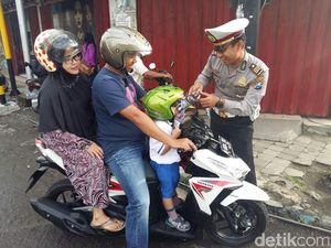 Polisi Bagi-bagi Buku dan Coklat untuk Anak yang Pakai Helm