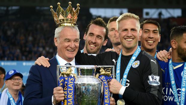 LEICESTER, ENGLAND - MAY 07:  Claudio Ranieri poses with the Premier League Trophy while Kasper Schmeichel puts the crown on the head of the manager as players and staffs celebrate the season champions after the Barclays Premier League match between Leicester City and Everton at The King Power Stadium on May 7, 2016 in Leicester, United Kingdom.  (Photo by Michael Regan/Getty Images)