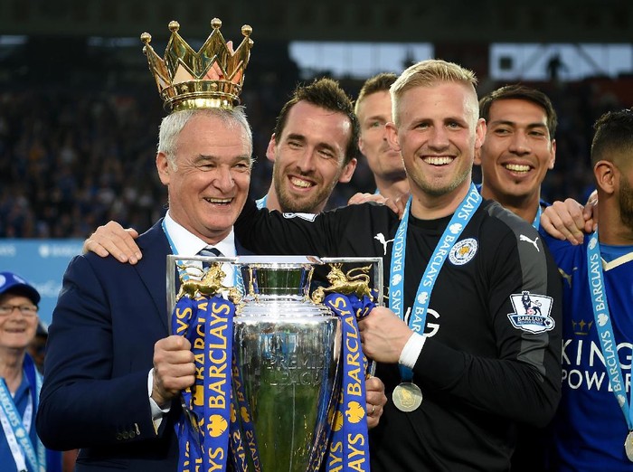 LEICESTER, ENGLAND - MAY 07:  Claudio Ranieri poses with the Premier League Trophy while Kasper Schmeichel puts the crown on the head of the manager as players and staffs celebrate the season champions after the Barclays Premier League match between Leicester City and Everton at The King Power Stadium on May 7, 2016 in Leicester, United Kingdom.  (Photo by Michael Regan/Getty Images)