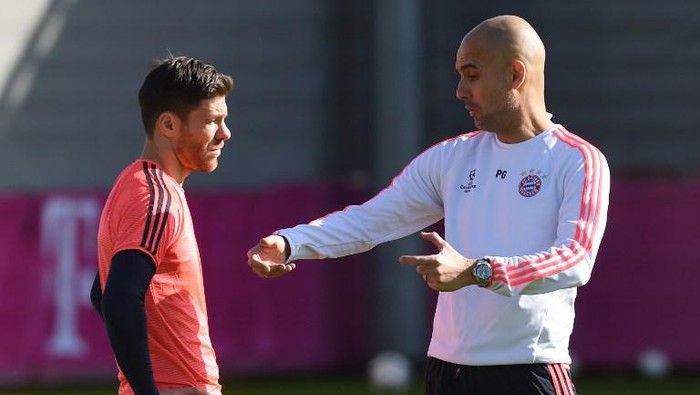 Bayern Munichs Spanish head coach Pep Guardiola (R) talks with Bayern Munichs Spanish midfielder Xabi Alonso (L) during the last team trainings session one day before the Champions League last 16, first-leg match between Juventus Turin and Bayern Munich at the trainings field in Munich, southern Germany, on February 22, 2016. / AFP PHOTO / CHRISTOF STACHE