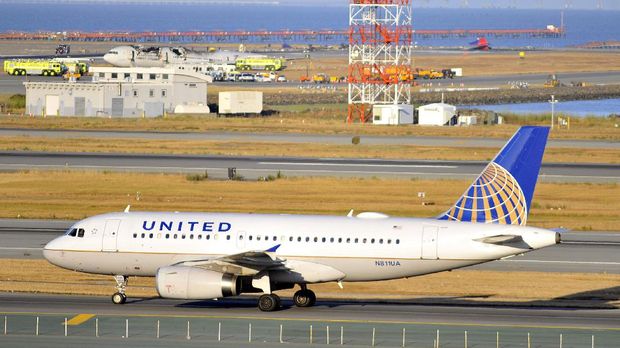A United Airlines plane taxis on the runway while a crashed Asiana Airlines Boeing 777 is seen on the runway (BACKGROUND) at San Francisco International Airport on Saturday, July, 06, 2013.  At least two people were killed and 130 injured when an Asiana Airlines Boeing 777 jet crashed and caught fire as it landed short of the runway. Another 60 people were still unaccounted for, the city's fire chief Joanne Hayes-White told reporters. It was not immediately clear if those people were presumed dead or had left the scene without alerting officials.    AFP PHOTO/JOSH EDELSON / AFP PHOTO / Josh Edelson