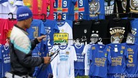 Seorang pedagang atribut Persib merapikan kaos yang dijualnya.