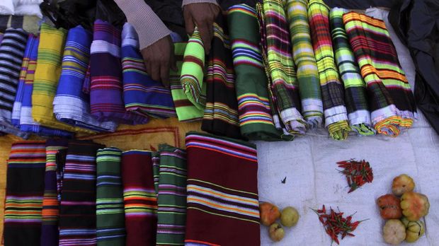 Pedagang mengatur sarung tenun khas Muna di pasar tradisional di Desa Mantobua, Kabupaten Muna, Sulawesi Tenggara, Jumat (7/4). Sarung tenun khas Muna tersebut dijual seharga Rp150 ribu sampai Rp250 ribu per lembar, tergantung jenis bahan dan motif. ANTARA FOTO/Jojon/kye/17.