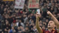 Legenda AS Roma, Francesco Totti, merayakan golnya ke gawang Lazio pada musim 2015 dengan berselfie dengan telepon pintarnya di depan pendukungnya. Itu menjadi aksi Totti yang paling dikenang. (Foto: AFP/Getty Images)