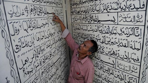 Warga mengamati tulisan Arab Alquran di Masjid Sapuro, Pekalongan, Jawa Tengah, Jumat (2/6). Alquran tulisan Arab berukuran panjang 2,4 meter dan lebar 2 meter yang terbuat dari triplek tersebut merupakan replika Alquran dari aslinya yang sebelumnya dihibahkan dari seorang komisaris polisi yaitu Moch Aswantary sekitar tahun 1970 di masjid tertua di Pekalongan tersebut. ANTARA FOTO/Harviyan Perdana Putra/ama/17