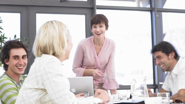 Businesswomen and men laughing sitting at conference table