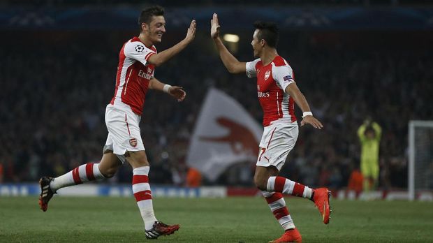 Arsenal's Chilean striker Alexis Sanchez (R) celebrates scoring his goal with Arsenal's German midfielder Mesut Ozil (L) during the UEFA Champions League, Group D football match between Arsenal and Galatasaray at The Emirates Stadium in north London on October 1, 2014. Arsenal won the game 4-1. AFP PHOTO / ADRIAN DENNIS / AFP PHOTO / ADRIAN DENNIS