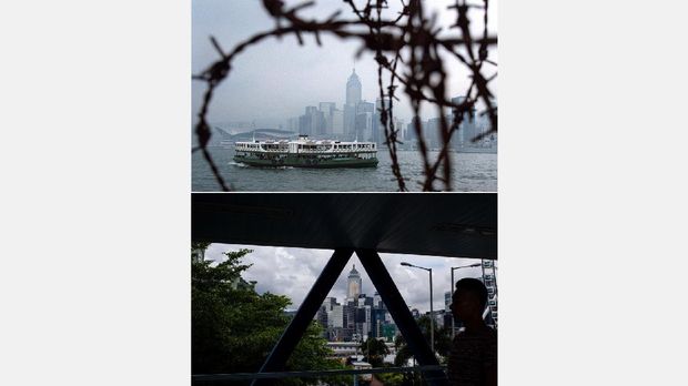 (COMBO) This combo shows a handout photo (top) taken on June 12, 1997 of rusty barbed wire framing the Star Ferry and Hong Kong's skyline along the waterfront of Victoria Harbour in Hong Kong and a photo (bottom) taken on June 9, 2017 of a man walking on a footbridge over reclaimed land which used to be part of the waterfront of Victoria Harbour in Hong Kong.
Hong Kong will mark the 20th anniversary of the handover from British to Chinese rule on July 1, 2017.  / AFP PHOTO / STEPHEN SHAVER AND Anthony WALLACE